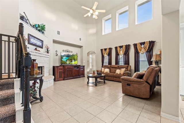 1115 Tydeman Ct, Katy, TX 77494 - living room with ceiling fan, a towering ceiling, light tile patterned floors, stairs, and arched walkways
