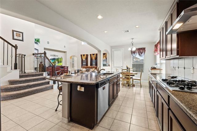 1115 Tydeman Ct, Katy, TX 77494 - kitchen featuring extractor fan, stainless steel appliances, a kitchen bar, arched walkways, and dark countertops