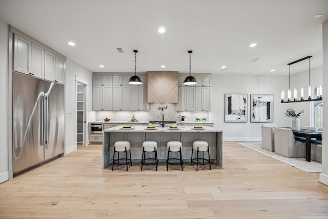 608 E 25th St, Houston, TX 77008 - kitchen featuring stainless steel appliances, light wood-type flooring, premium range hood, tasteful backsplash, and recessed lighting
