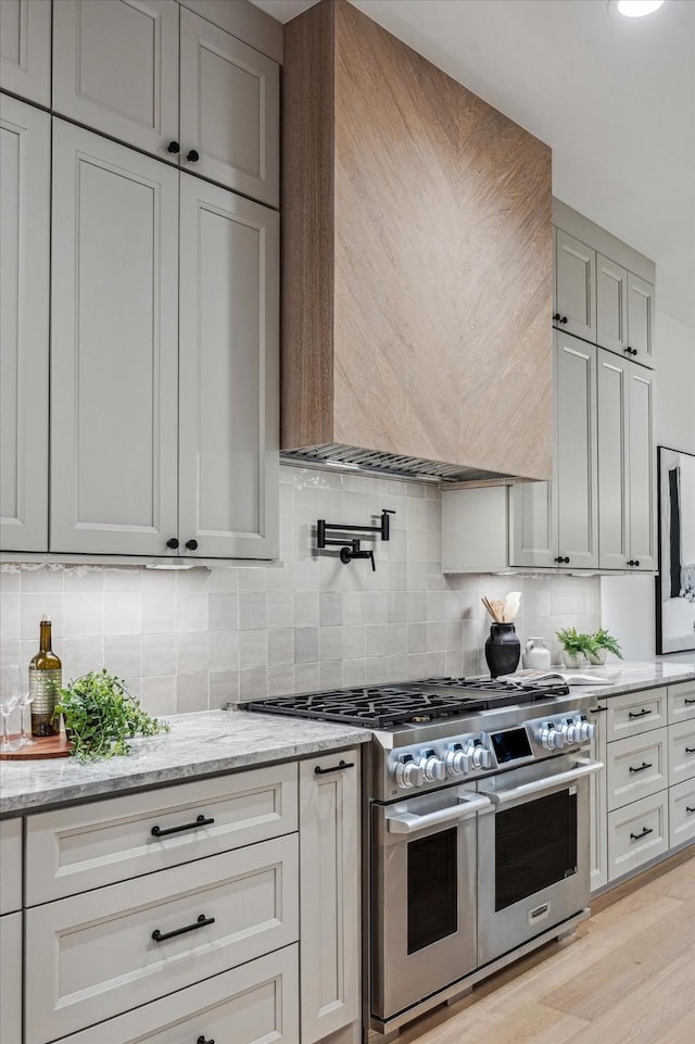 608 E 25th St, Houston, TX 77008 - kitchen featuring double oven range, premium range hood, backsplash, light stone counters, and light wood-style flooring