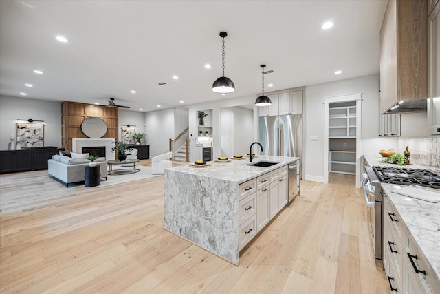 608 E 25th St, Houston, TX 77008 - kitchen featuring appliances with stainless steel finishes, light wood finished floors, recessed lighting, a fireplace, and light stone countertops