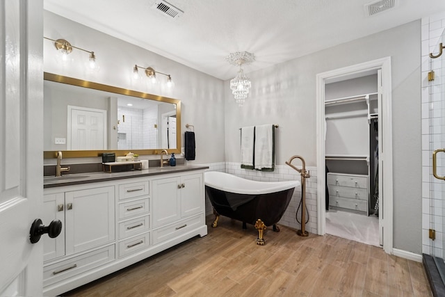 87 E Greenhill Terrace Pl, The Woodlands, TX 77382 - bathroom with a shower stall, double vanity, a chandelier, wood finished floors, and tile walls