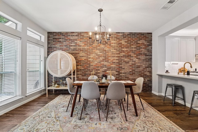 87 E Greenhill Terrace Pl, The Woodlands, TX 77382 - dining room featuring dark wood-style flooring, a chandelier, and brick wall