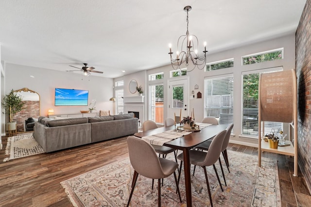 87 E Greenhill Terrace Pl, The Woodlands, TX 77382 - dining room featuring a fireplace, a chandelier, wood finished floors, and a ceiling fan
