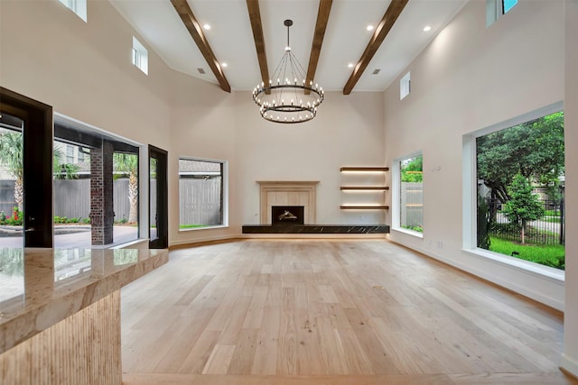 4316 Dickson St, Houston, TX 77007 - unfurnished living room featuring a chandelier, a towering ceiling, beam ceiling, light wood-type flooring, and a tiled fireplace