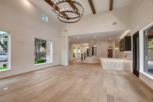 4316 Dickson St, Houston, TX 77007 - unfurnished living room with stairs, a towering ceiling, a chandelier, light wood finished floors, and beamed ceiling