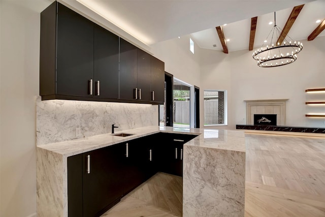 4316 Dickson St, Houston, TX 77007 - kitchen featuring dark cabinetry, beamed ceiling, light stone countertops, tasteful backsplash, and a chandelier