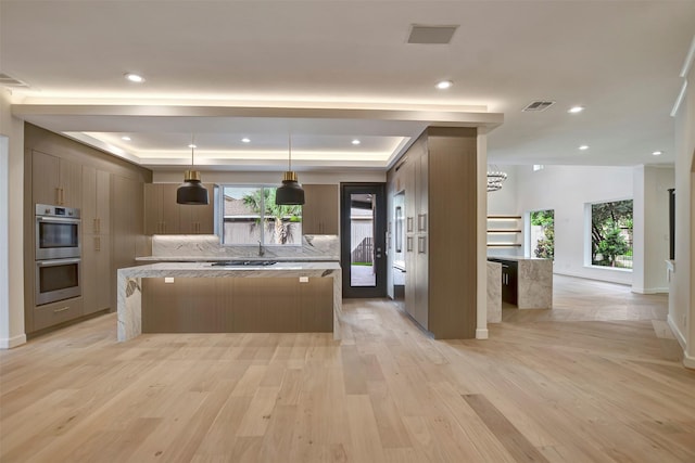 4316 Dickson St, Houston, TX 77007 - kitchen featuring double oven, a center island, a raised ceiling, light wood-style flooring, and modern cabinets