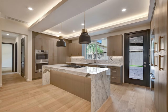 4316 Dickson St, Houston, TX 77007 - kitchen featuring appliances with stainless steel finishes, light wood finished floors, a kitchen island, decorative backsplash, and a tray ceiling