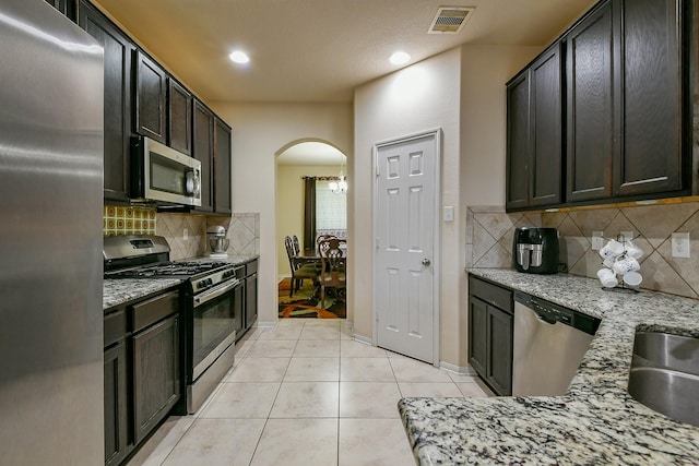 4134 Loft Square Pl, Humble, TX 77346 - kitchen with stainless steel appliances, arched walkways, tasteful backsplash, light tile patterned floors, and recessed lighting