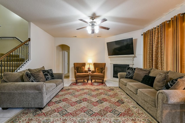 4134 Loft Square Pl, Humble, TX 77346 - living room with light tile patterned flooring, arched walkways, ceiling fan, a glass covered fireplace, and stairway