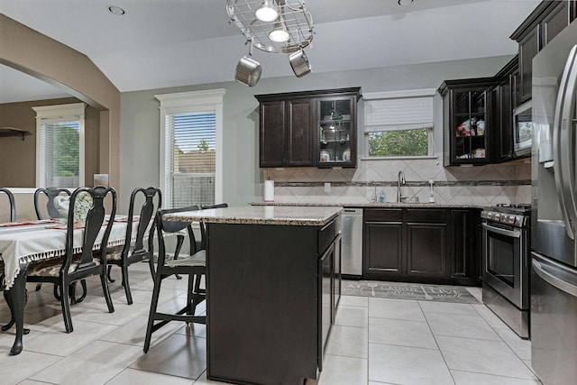 18819 Deer Trace Dr, Crosby, TX 77532 - kitchen featuring stainless steel appliances, light stone counters, decorative backsplash, glass insert cabinets, and arched walkways