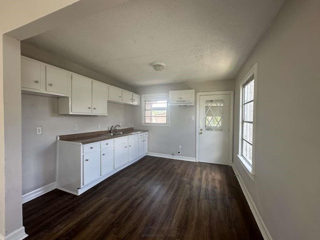 7410 Dallas St, Houston, TX 77011 - kitchen featuring dark wood finished floors, a textured ceiling, white cabinetry, and dark countertops
