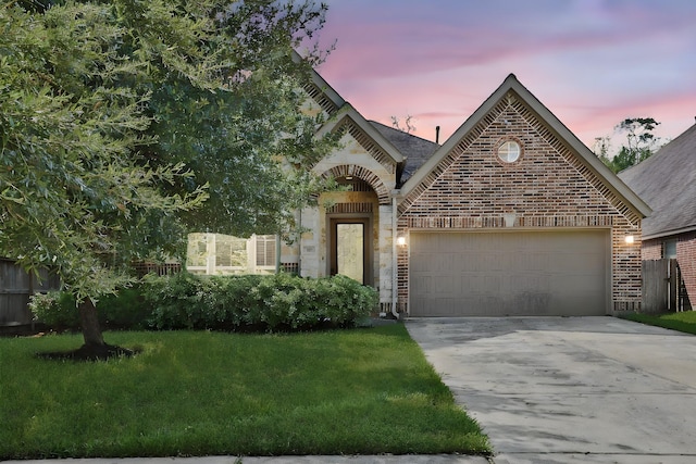 23414 Fauburg Dr, New Caney, TX 77357 - view of front of property with brick siding, concrete driveway, a garage, a front lawn, and stone siding