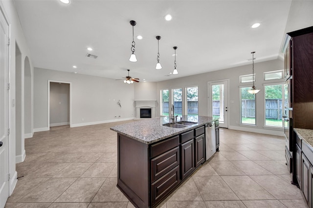 23414 Fauburg Dr, New Caney, TX 77357 - kitchen with a glass covered fireplace, stainless steel appliances, a ceiling fan, dark brown cabinets, and light tile patterned floors
