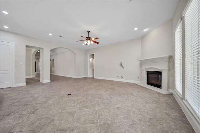 23414 Fauburg Dr, New Caney, TX 77357 - unfurnished living room featuring ceiling fan, a glass covered fireplace, recessed lighting, arched walkways, and light tile patterned flooring