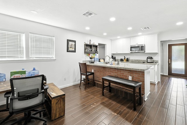 15110 Runbell Pl, Houston, TX 77095 - kitchen featuring stainless steel microwave, a kitchen breakfast bar, white cabinets, a peninsula, and dark wood-style flooring