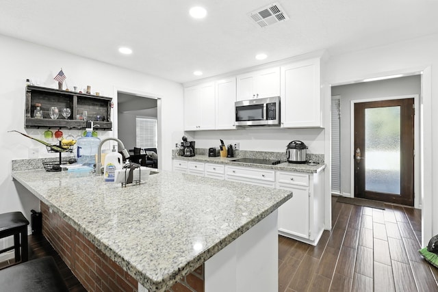 15110 Runbell Pl, Houston, TX 77095 - kitchen featuring stainless steel microwave, black electric stovetop, white cabinets, wood tiled floors, and recessed lighting