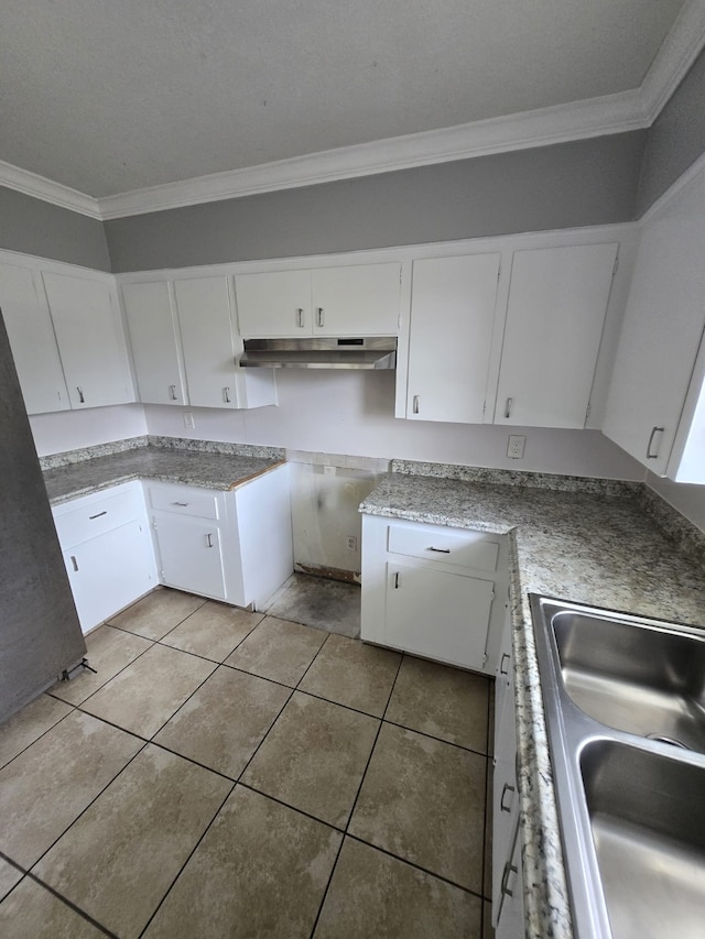 6814 Della St, Houston, TX 77093 - kitchen with ornamental molding, under cabinet range hood, light tile patterned floors, white cabinetry, and light countertops