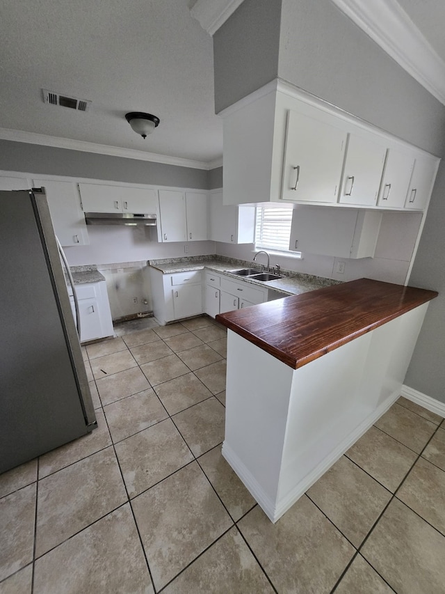 6814 Della St, Houston, TX 77093 - kitchen featuring freestanding refrigerator, a peninsula, ornamental molding, light tile patterned floors, and white cabinetry