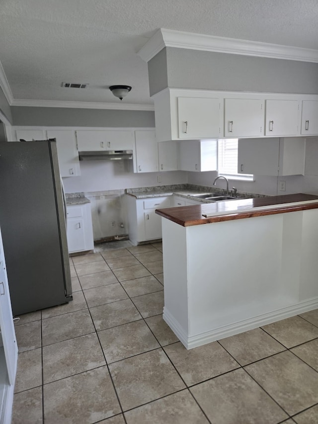 6814 Della St, Houston, TX 77093 - kitchen featuring freestanding refrigerator, crown molding, a textured ceiling, white cabinets, and light tile patterned floors