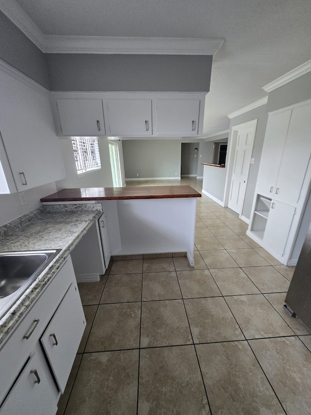 6814 Della St, Houston, TX 77093 - kitchen with crown molding, light tile patterned floors, and white cabinetry