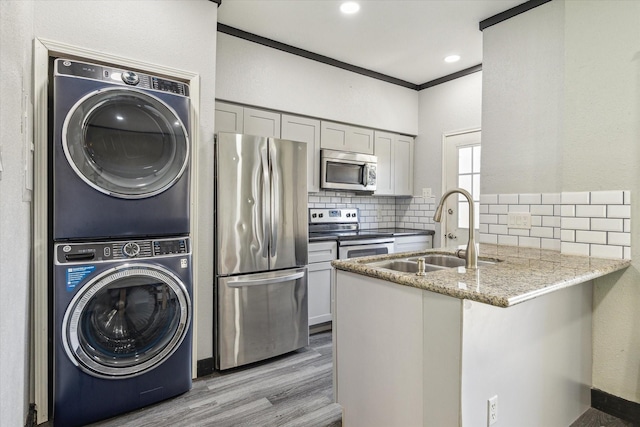 3600 Jeanetta St Unit 1902, Houston, TX 77063 - kitchen featuring stainless steel appliances, stacked washer and clothes dryer, a peninsula, light wood finished floors, and tasteful backsplash