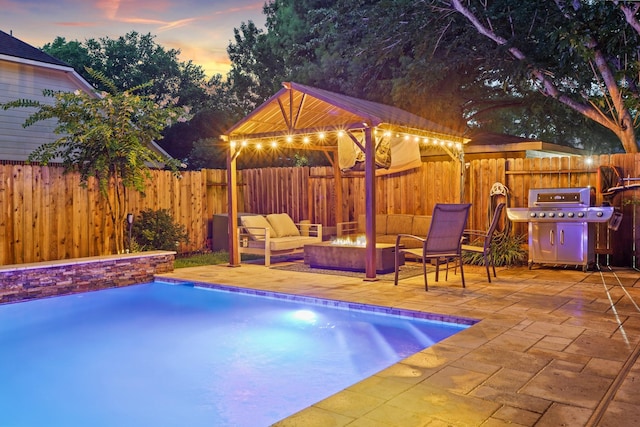 16403 Bogan Flats Ct, Houston, TX 77095 - pool at dusk with area for grilling, a patio area, a gazebo, an outdoor living space with a fire pit, and a fenced backyard