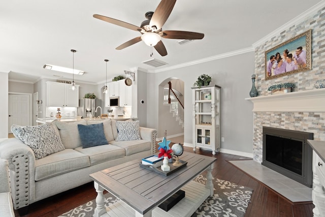 16403 Bogan Flats Ct, Houston, TX 77095 - living area with ceiling fan, arched walkways, a tiled fireplace, stairway, and dark wood-type flooring