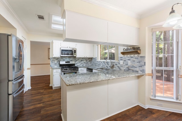 34 Sweetdream Pl, The Woodlands, TX 77381 - kitchen with stainless steel appliances, a peninsula, dark wood finished floors, light stone counters, and tasteful backsplash