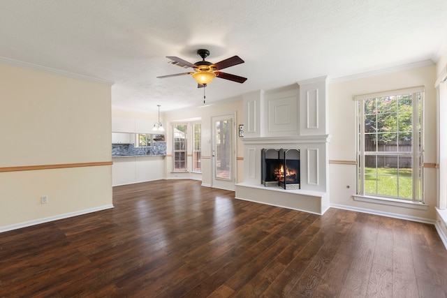 34 Sweetdream Pl, The Woodlands, TX 77381 - unfurnished living room with dark wood finished floors, ceiling fan, a warm lit fireplace, and crown molding