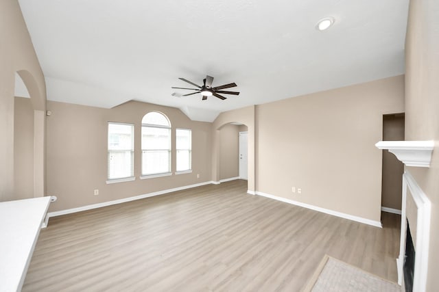 7407 Rustic Chase Dr, Richmond, TX 77407 - unfurnished living room featuring a ceiling fan, arched walkways, light wood finished floors, and vaulted ceiling