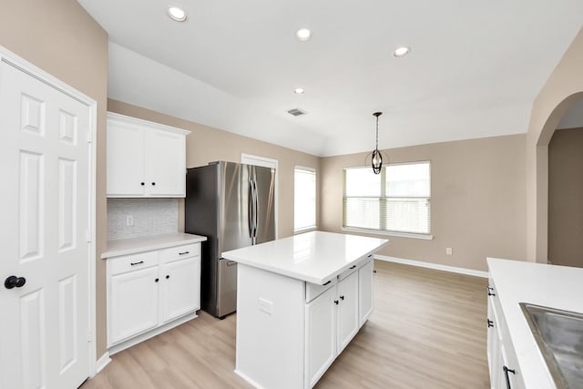 7407 Rustic Chase Dr, Richmond, TX 77407 - kitchen featuring freestanding refrigerator, arched walkways, light wood-style floors, a kitchen island, and light countertops