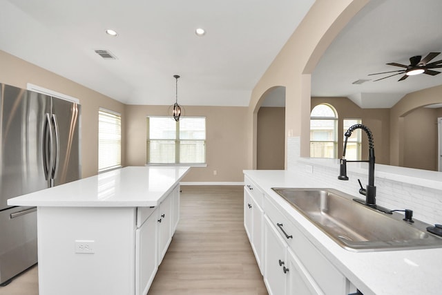 7407 Rustic Chase Dr, Richmond, TX 77407 - kitchen featuring freestanding refrigerator, vaulted ceiling, arched walkways, decorative backsplash, and light countertops