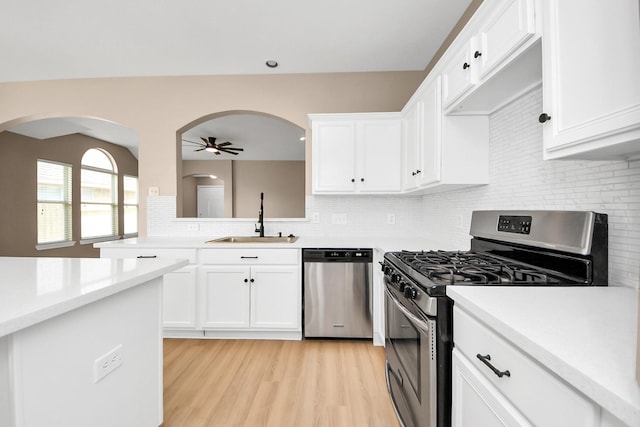 7407 Rustic Chase Dr, Richmond, TX 77407 - kitchen featuring stainless steel appliances, a ceiling fan, light countertops, arched walkways, and backsplash