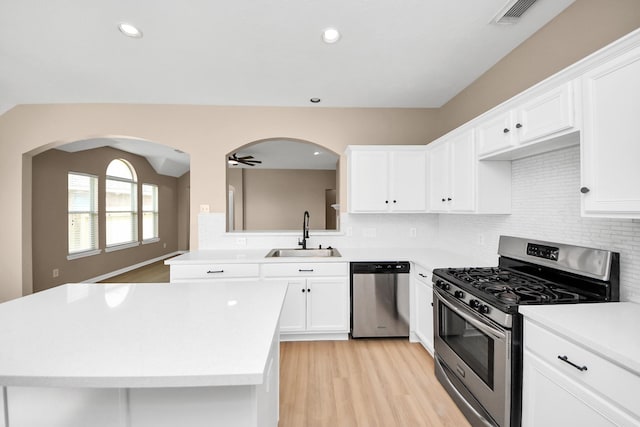 7407 Rustic Chase Dr, Richmond, TX 77407 - kitchen with stainless steel appliances, light countertops, light wood-style floors, white cabinetry, and backsplash