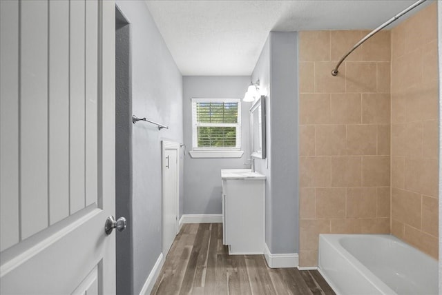 3217 Michigan St, Baytown, TX 77520 - bathroom with vanity, wood finished floors, bathtub / shower combination, and a textured ceiling
