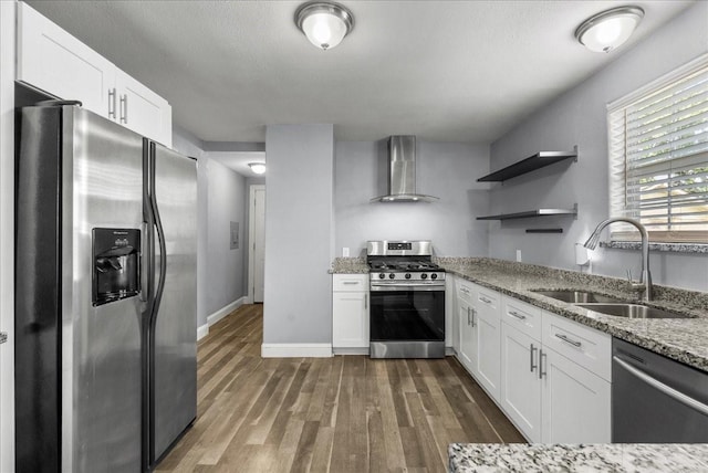 3217 Michigan St, Baytown, TX 77520 - kitchen featuring appliances with stainless steel finishes, wall chimney range hood, dark wood finished floors, light stone countertops, and white cabinetry