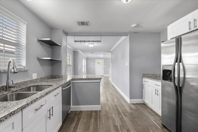3217 Michigan St, Baytown, TX 77520 - kitchen featuring appliances with stainless steel finishes, ornamental molding, dark wood-type flooring, white cabinetry, and a peninsula