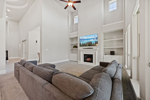 16715 Bark Cabin Dr, Humble, TX 77346 - living room featuring a towering ceiling, built in shelves, carpet, a glass covered fireplace, and a ceiling fan