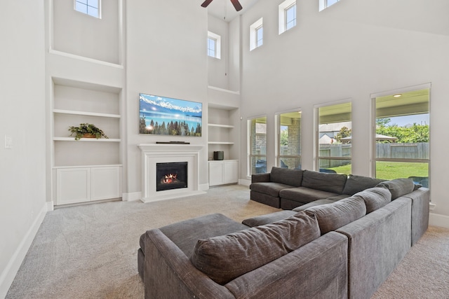 16715 Bark Cabin Dr, Humble, TX 77346 - carpeted living area with built in features, a towering ceiling, ceiling fan, and a warm lit fireplace