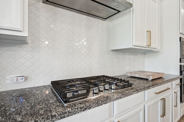 16715 Bark Cabin Dr, Humble, TX 77346 - kitchen featuring stainless steel gas cooktop, decorative backsplash, range hood, white cabinets, and dark stone counters