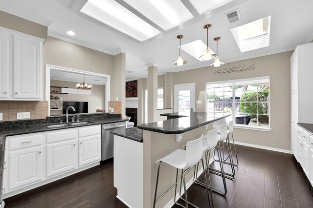 35 S Floral Leaf Cir, The Woodlands, TX 77381 - kitchen featuring stainless steel dishwasher, a skylight, dark wood-style flooring, white cabinets, and crown molding
