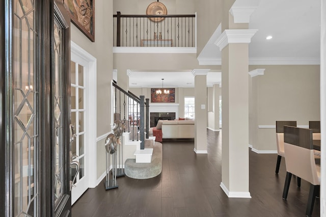 35 S Floral Leaf Cir, The Woodlands, TX 77381 - entryway with decorative columns, a fireplace, ornamental molding, a chandelier, and dark wood-style floors