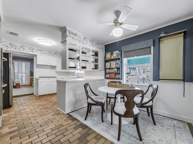 10610 Piping Rock Ln, Houston, TX 77042 - dining space with plenty of natural light, a ceiling fan, brick patterned flooring, a wainscoted wall, and ornamental molding