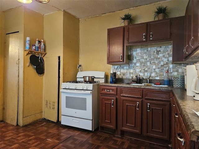 6504 Ave J, Houston, TX 77011 - kitchen with white range with gas cooktop, decorative backsplash, and dark countertops