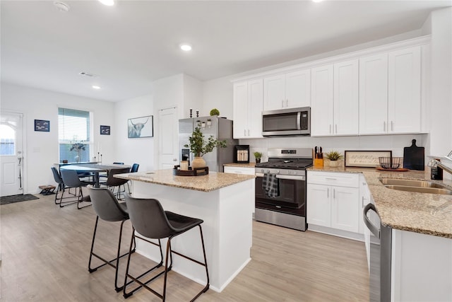 23823 Escardilla Ln, Hockley, TX 77447 - kitchen with stainless steel appliances, light wood-type flooring, a kitchen island, a kitchen breakfast bar, and recessed lighting