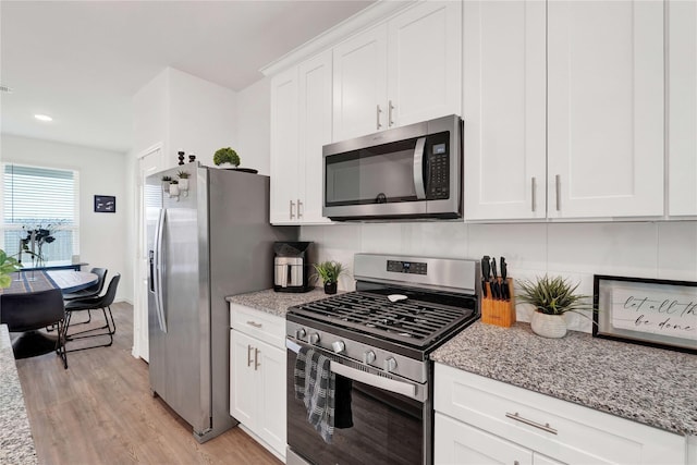 23823 Escardilla Ln, Hockley, TX 77447 - kitchen with appliances with stainless steel finishes, light wood-style flooring, white cabinets, backsplash, and light stone counters