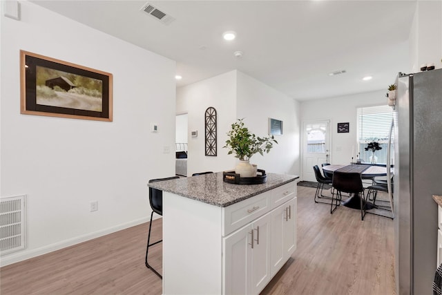23823 Escardilla Ln, Hockley, TX 77447 - kitchen with freestanding refrigerator, light wood-type flooring, a kitchen bar, white cabinets, and a center island