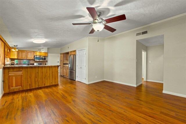 925 Royal Oak Dr, Dickinson, TX 77539 - kitchen with appliances with stainless steel finishes, a peninsula, dark wood finished floors, brown cabinetry, and a textured ceiling